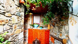 A stone-walled room with a wooden cabinet, a window with a curtain, and a potted plant. - Sirincem Pension (Selçuk)