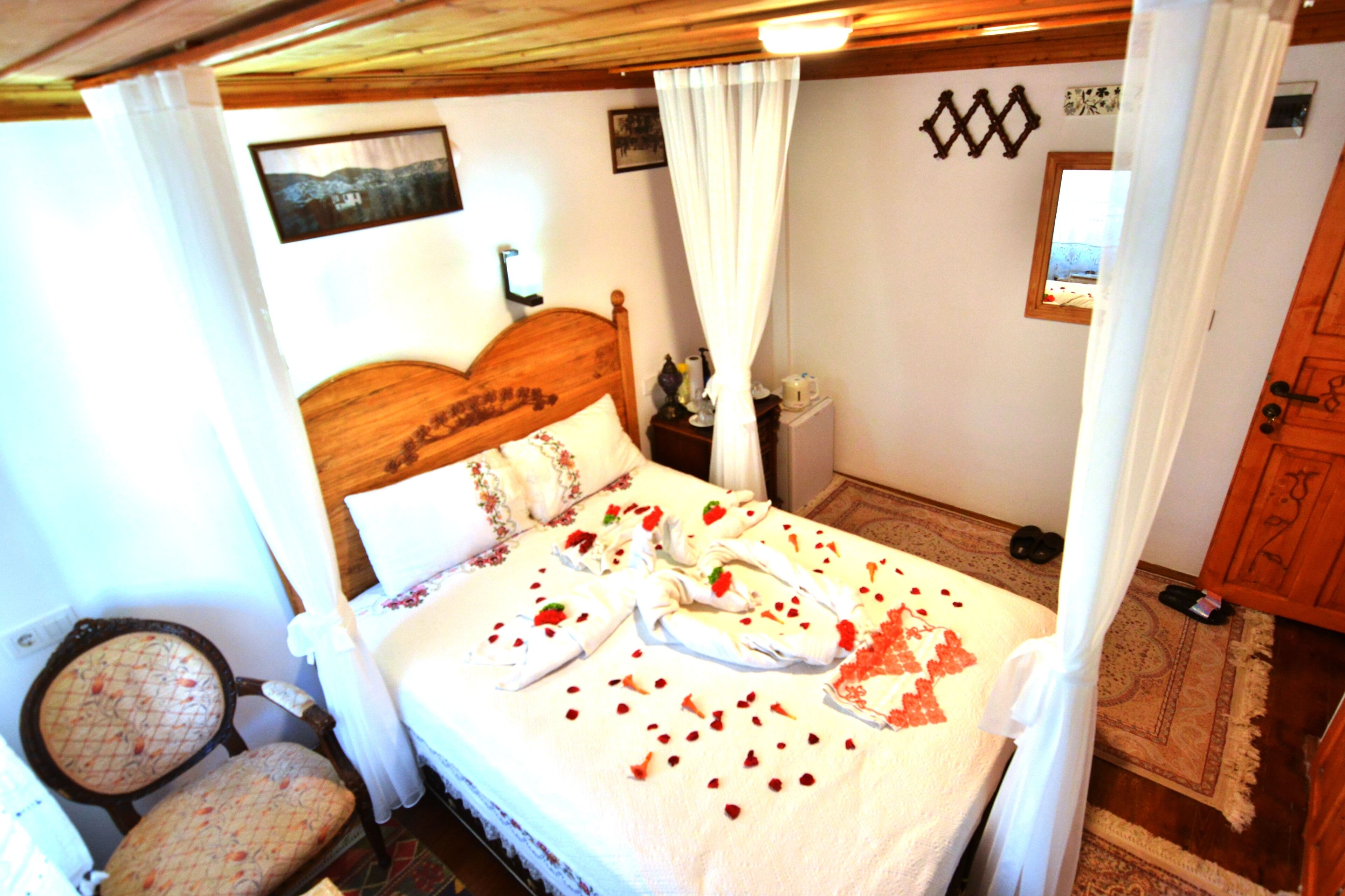 A neatly made bed with a canopy, a wooden headboard, and a nightstand with a lamp.