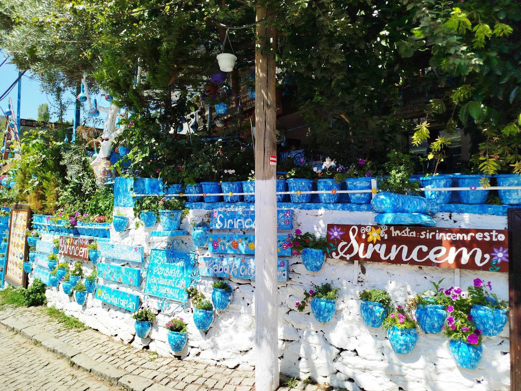 Un muro con fioriere blu e cartelli, tra cui uno per un ristorante.