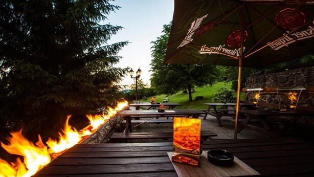 A wooden deck with a fire, picnic tables, and a stone wall. - Chata Pod Lipami (Rokytnice nad Jizerou)