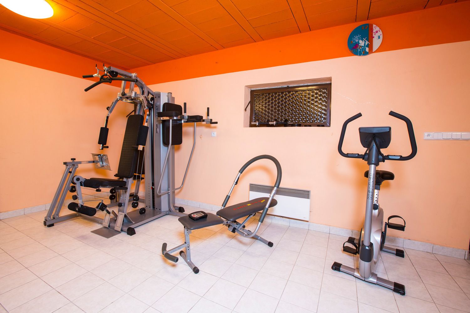 A gym with various exercise equipment including a bench press, a leg press, and a stationary bike.