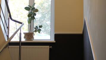 A staircase with a radiator and a window with a plant.