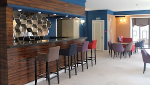 A bar area with a wooden counter and hexagonal mirrors, surrounded by multiple bar stools. - Non-Stop Hotel (Boryspil)