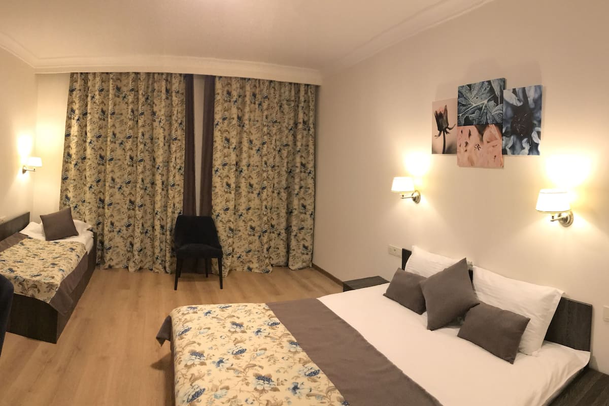 Ein Hotelzimmer mit zwei Betten, einem Schreibtisch, einem Stuhl und einem Fernseher.