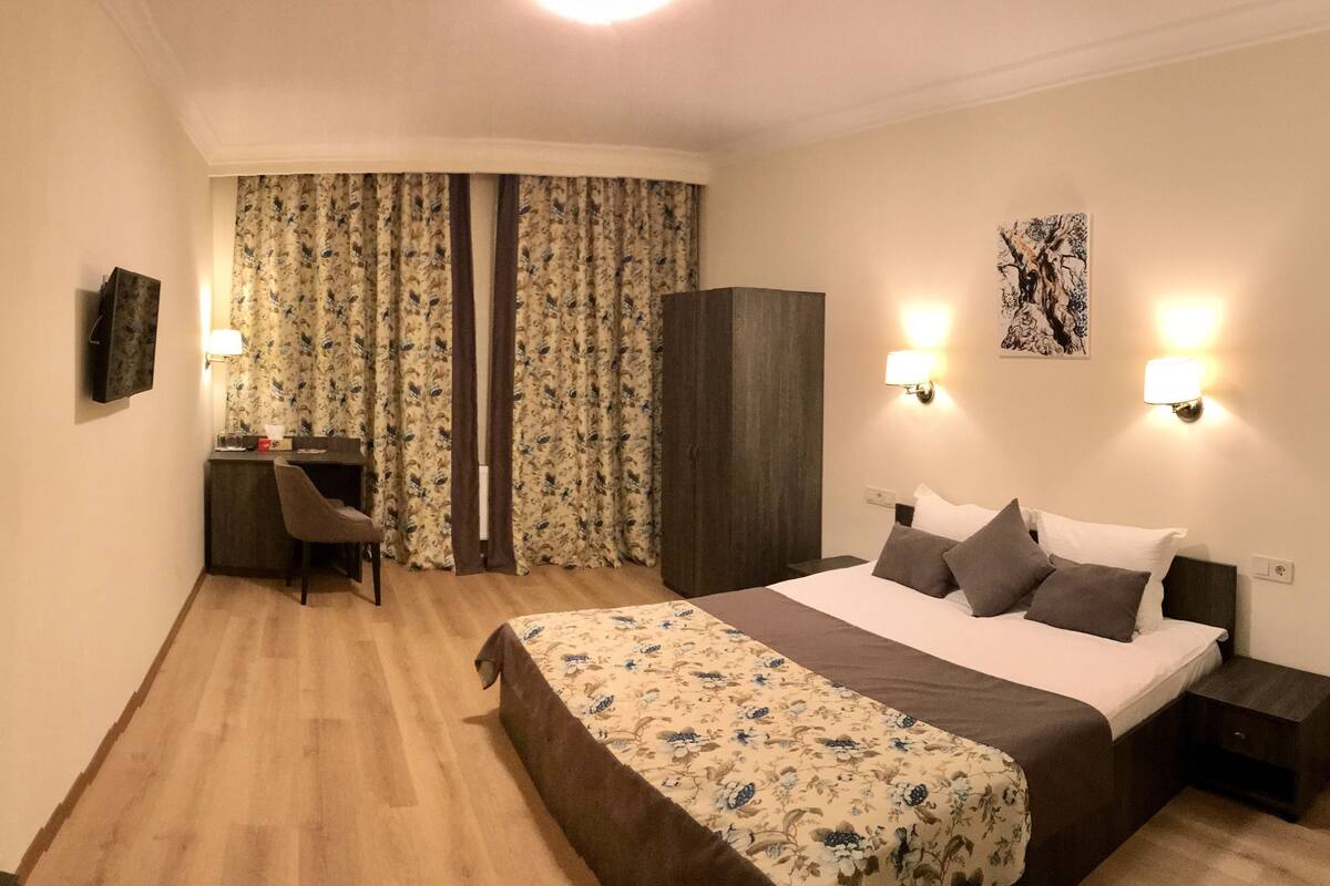 Ein Hotelzimmer mit einem Bett, einem Schreibtisch, einem Stuhl, einem Spiegel und einem Kleiderschrank.