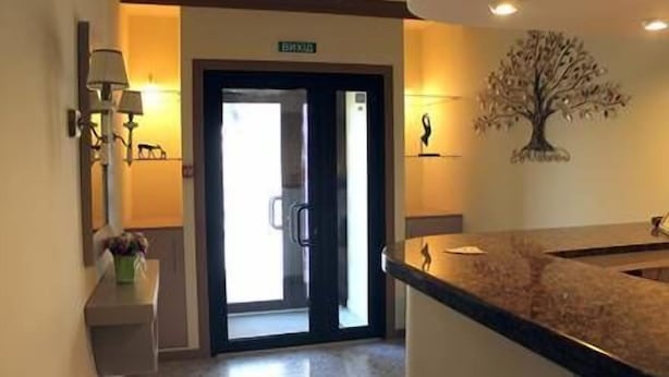 A hotel lobby with a reception desk, a door marked "EXIT", and a wall-mounted tree decoration. - Non-Stop Hotel (Boryspil)