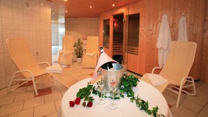 Una habitación con paredes de madera, piso de baldosas y una mesa con una botella de champán, dos copas y rosas.