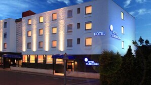 Un moderno edificio de hotel con varios pisos, ventanas iluminadas y un llamativo letrero que dice 'HOTEL SILBERHORN'.