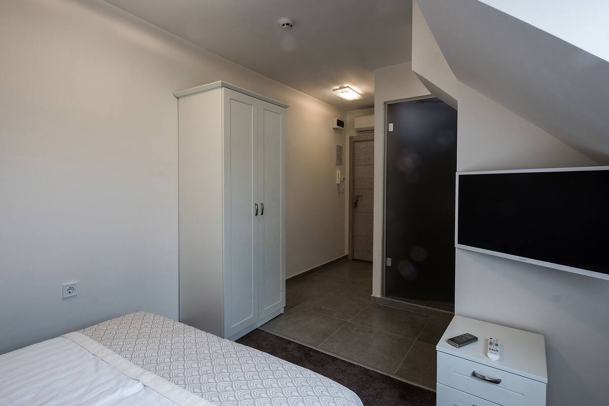 A bedroom with a bed, wardrobe, and a TV mounted on the wall.