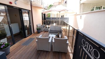 Un balcón con mobiliario de mimbre, una puerta de cristal y un cartel que dice 'Ciro Apartments'.