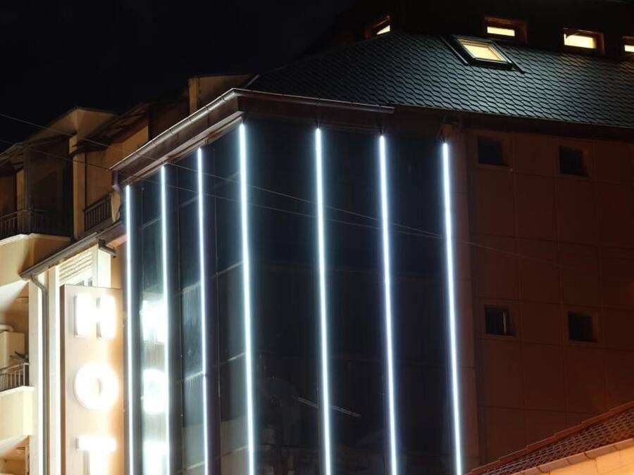 A hotel with a modern facade, illuminated signage, and a balcony.