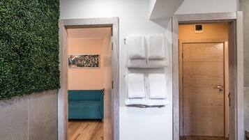 Un pasillo con pared verde, sofá turquesa, puerta blanca y puerta de madera.