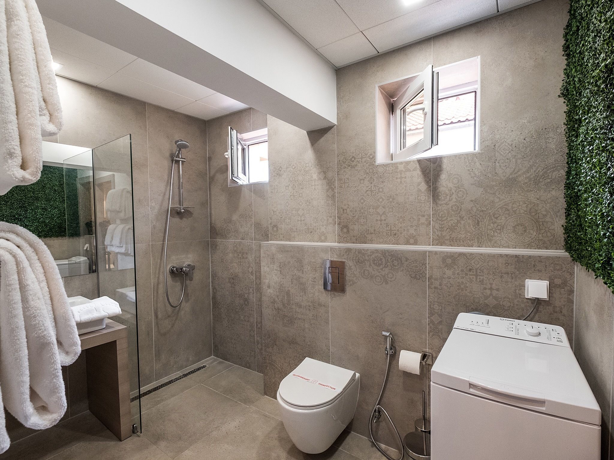 A modern bathroom with a glass shower enclosure, a toilet, and a washing machine.