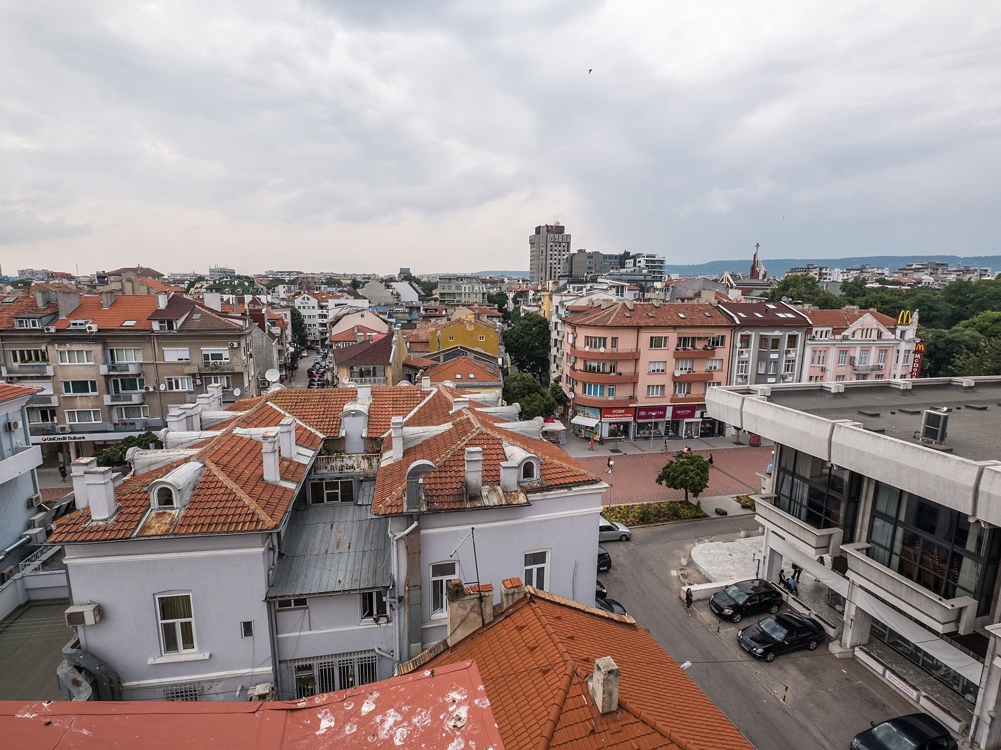 A cityscape with a variety of buildings, including residential and commercial structures with red-tiled roofs.