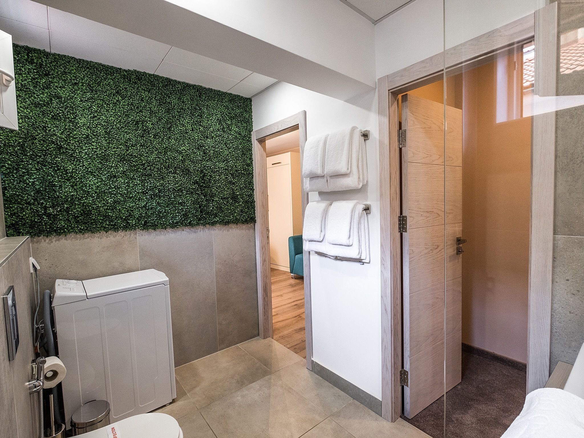 A modern bathroom with a green wall, a toilet, a sink, and a shower area.