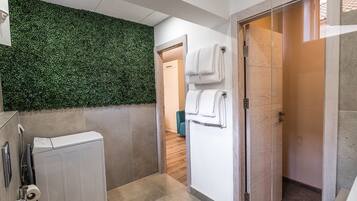 A modern bathroom with a green wall, a toilet, a sink, and a shower area.