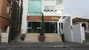 L’entrée d’un hôtel, avec une enseigne indiquant « Hôtel Victor Plaza » et « Aora do Almoço ».