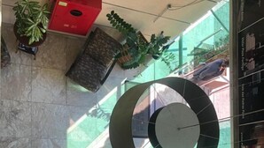 Un espace de bureau moderne avec un bureau en verre, deux chaises de bureau, une grande œuvre d’art abstraite et une plante en pot.