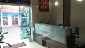 Un espace d’accueil avec un comptoir en verre, un téléphone et une chaise.