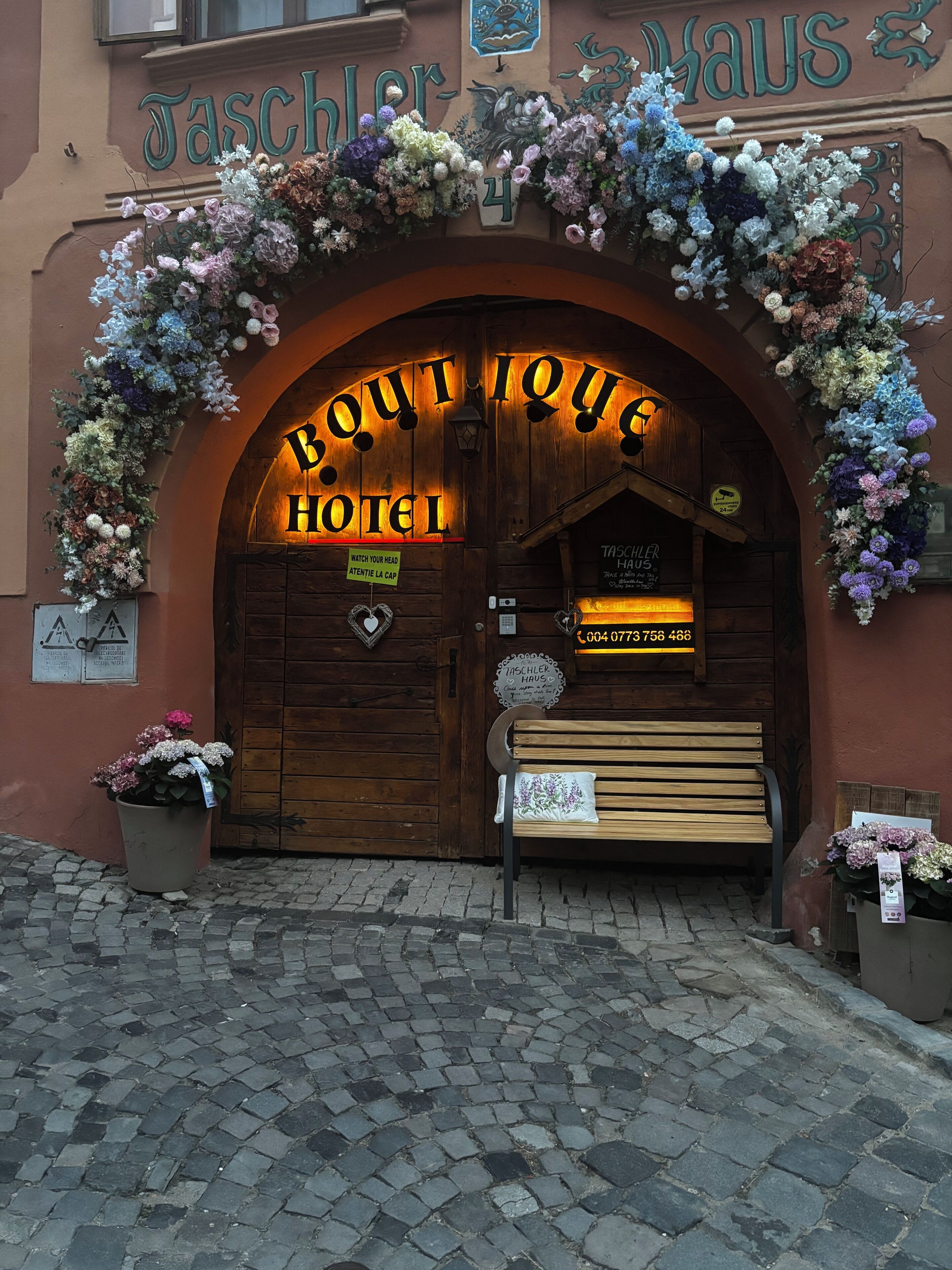 L'ingresso di un hotel con una porta in legno, una panchina all'esterno e un cartello sopra la porta.