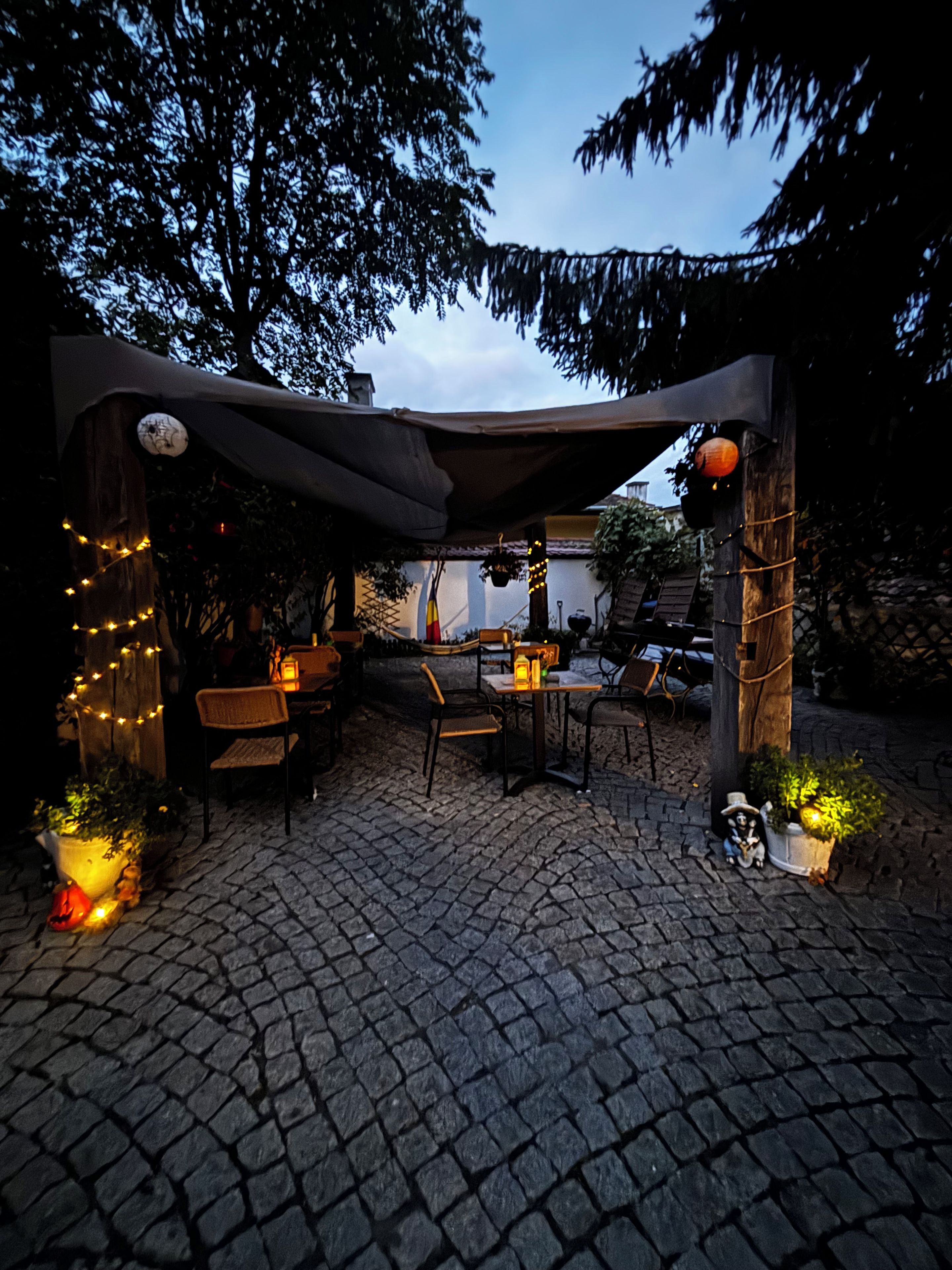 An outdoor patio area with a pergola, seating, and decorative lighting.