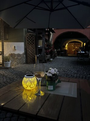 An outdoor seating area with a table, a glass of white wine, a decorative lantern, and a potted plant. - Taschler Haus Boutique (Sighisoara)