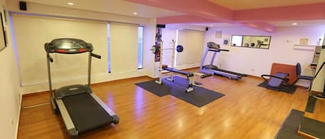 A gym with treadmills, a weight bench, and exercise mats.