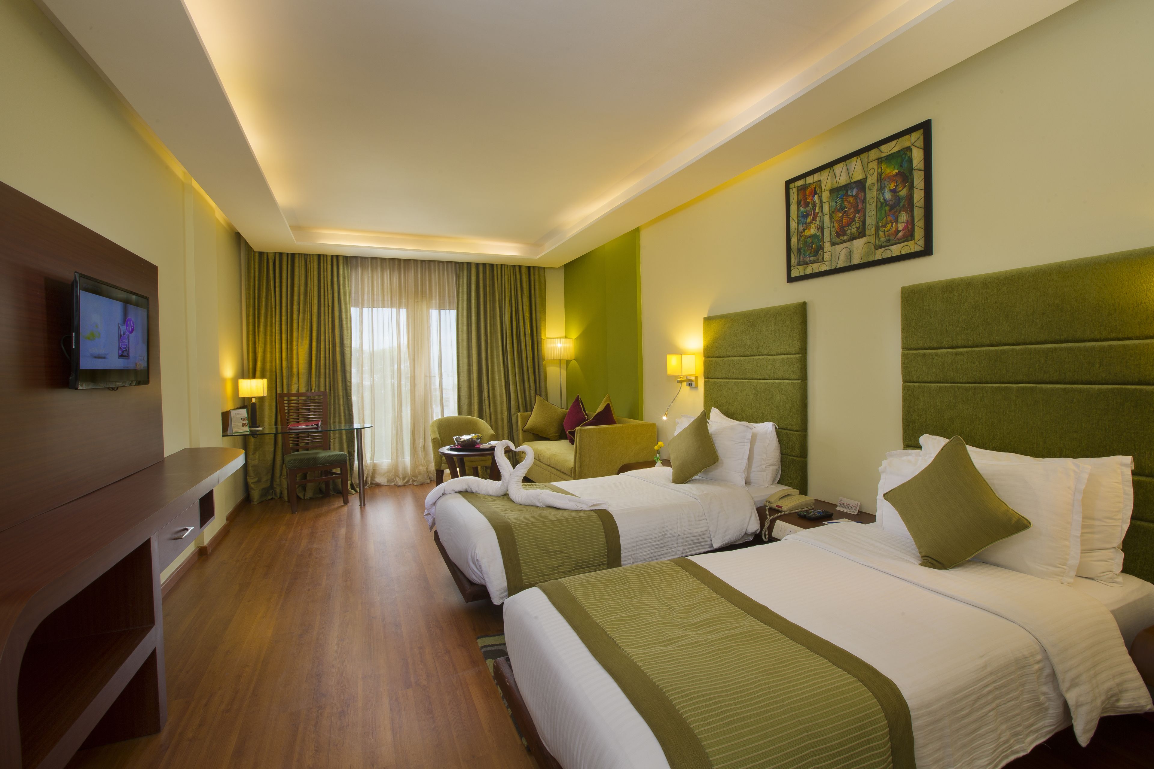 A hotel room with two beds, a TV, a desk, and a chair.