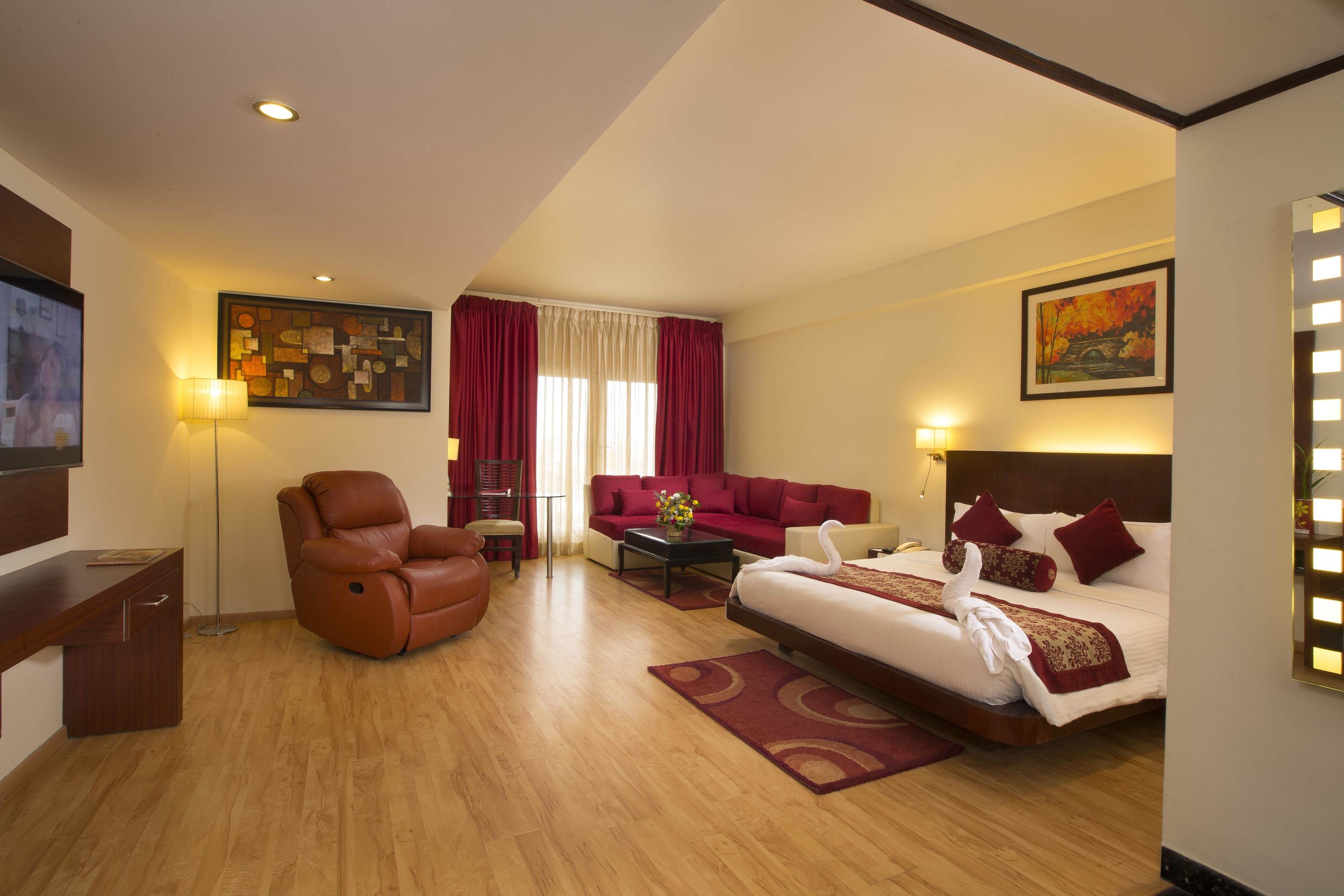Een hotelkamer met een bed, een bank, een stoel, een bureau en een televisie.