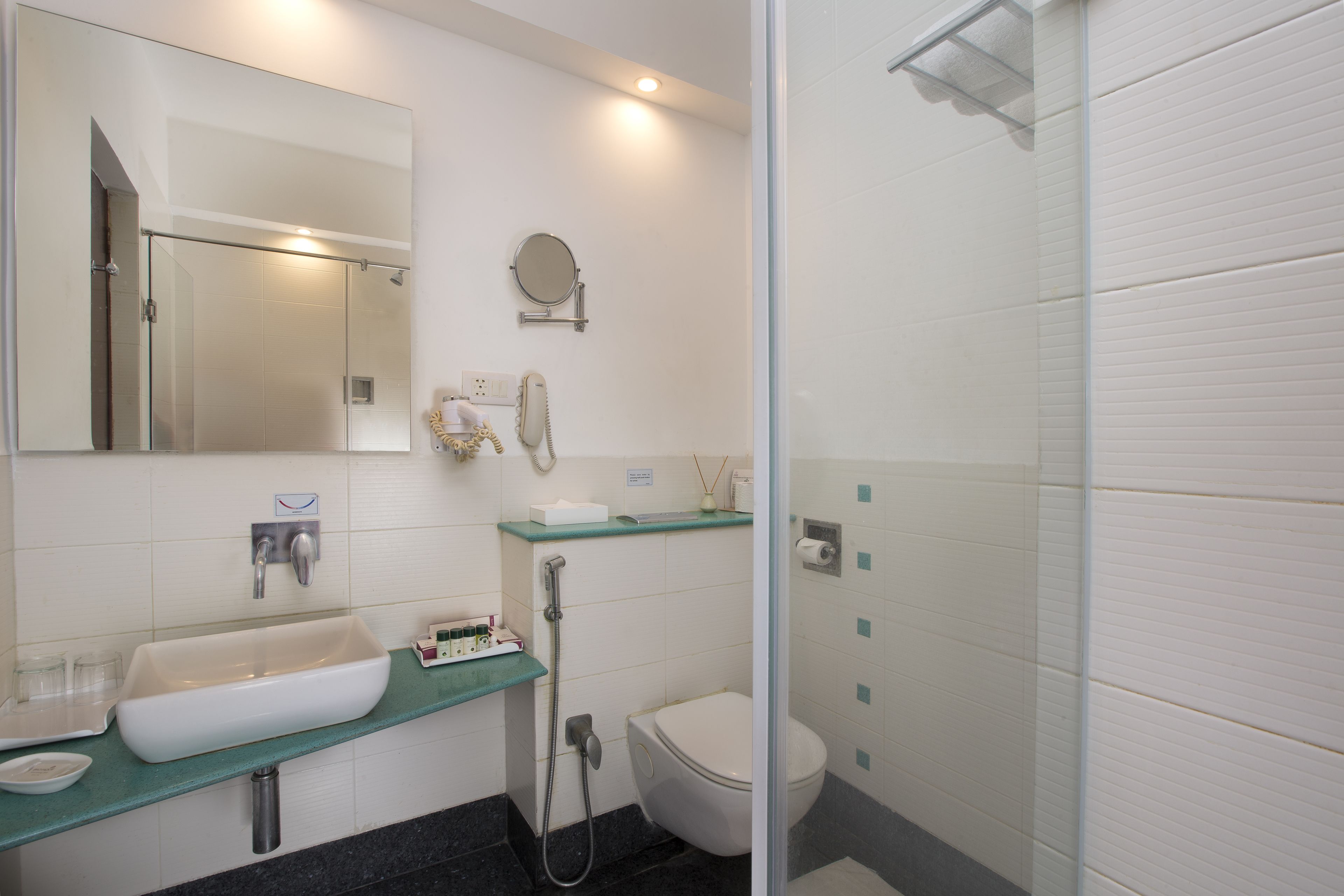 Uma casa de banho moderna com cabine de duche em vidro, lavatório branco e sanita.