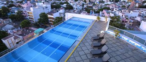 A rooftop swimming pool with a view of a densely built cityscape.