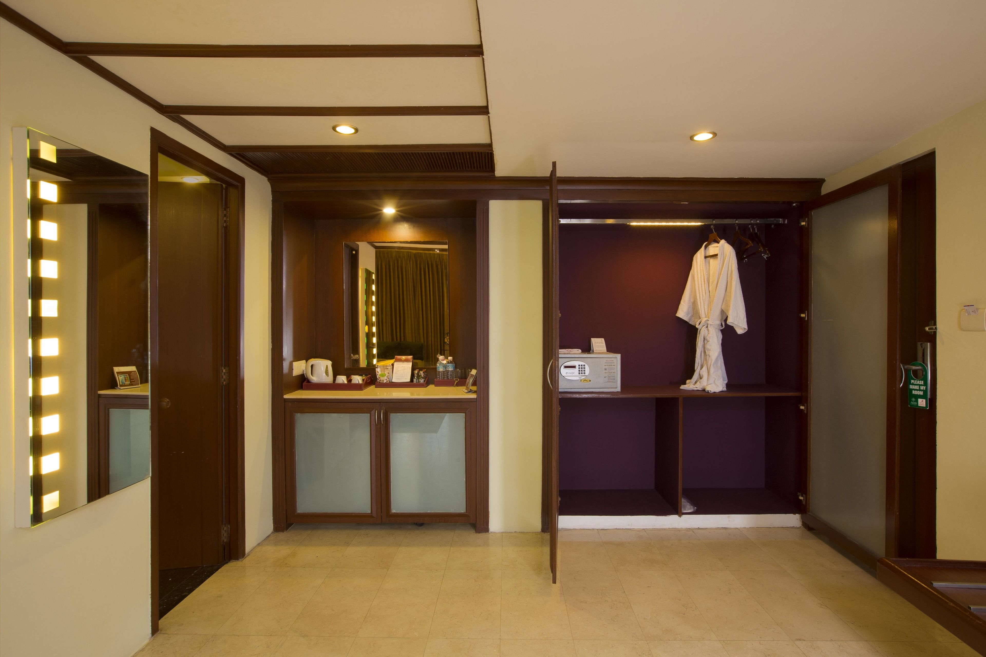 Habitación de hotel con tocador, una bata colgada en un perchero y un espejo con luces.