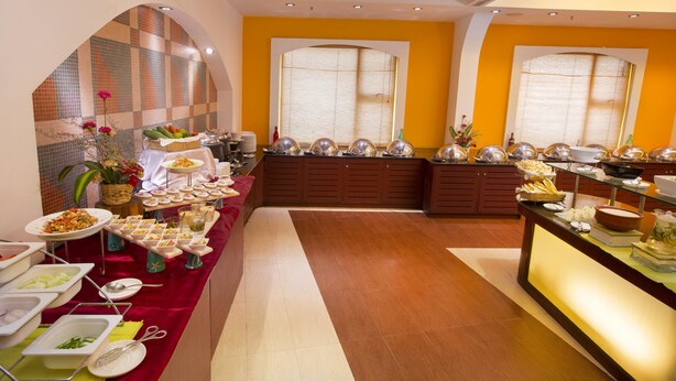 A buffet setup with various food items and serving utensils. - Hotel Atithi (Puducherry)