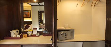 A hotel bathroom with a mirror, a sink, a microwave, and wooden hangers on a rack.
