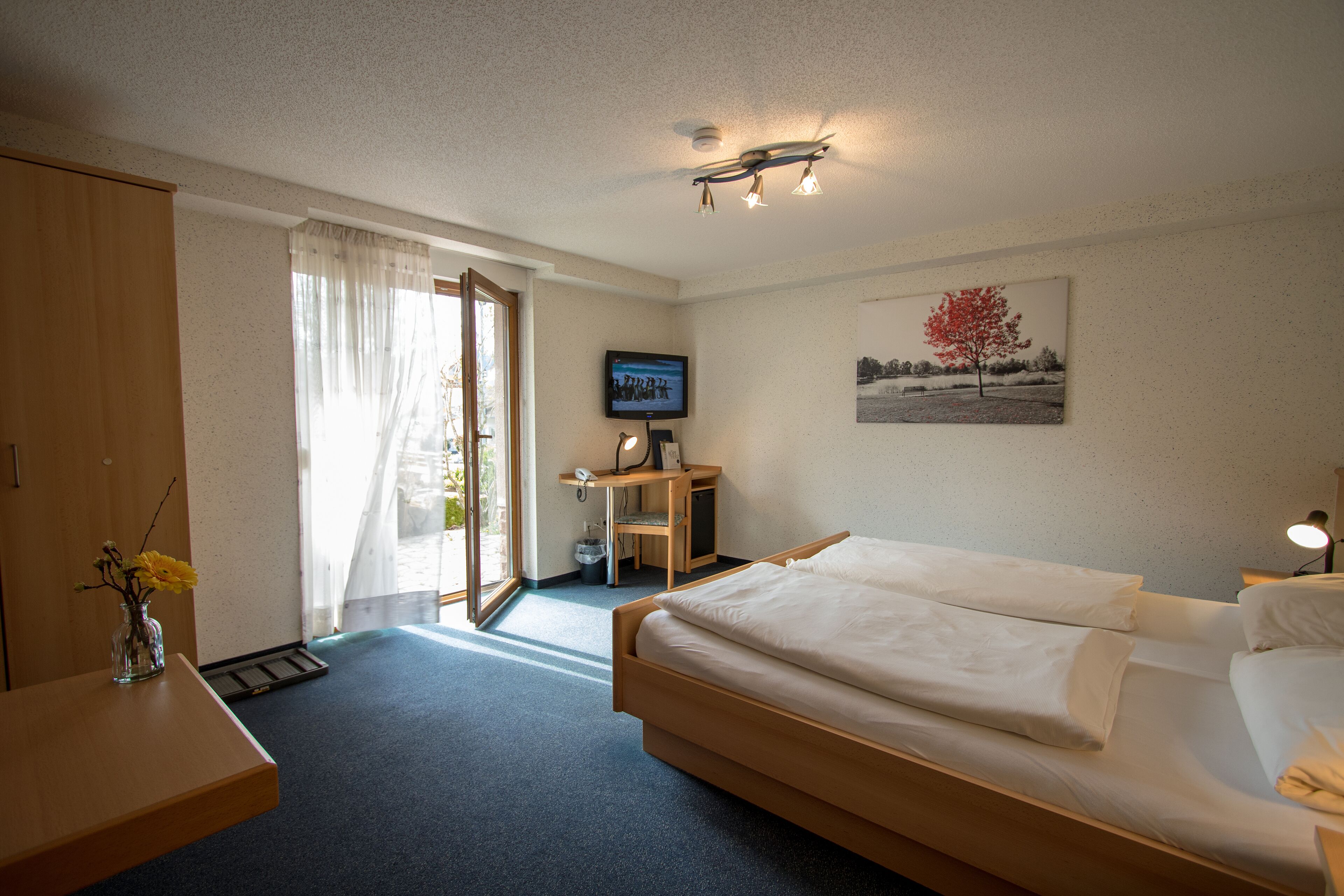 Habitación de hotel con cama, escritorio, silla y un cuadro en la pared.