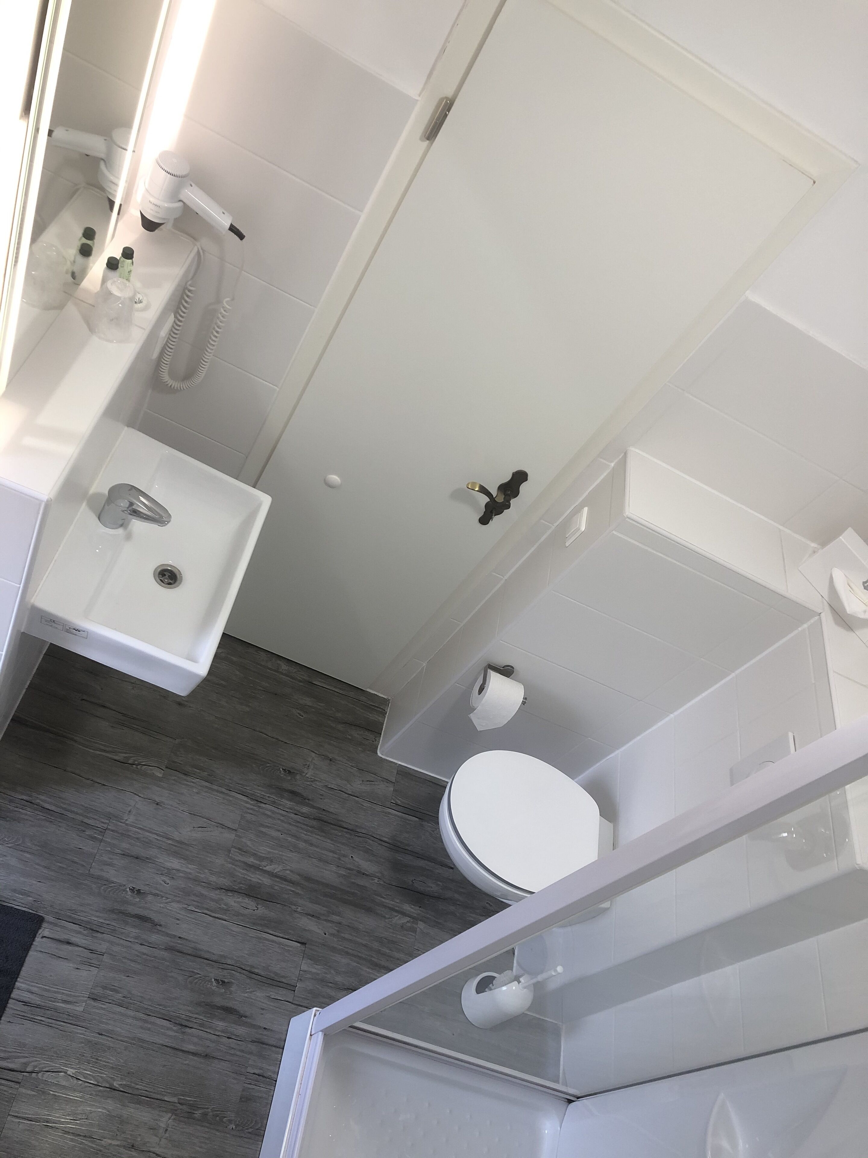 Uma casa de banho moderna com lavatório branco, sanita e zona de duche.