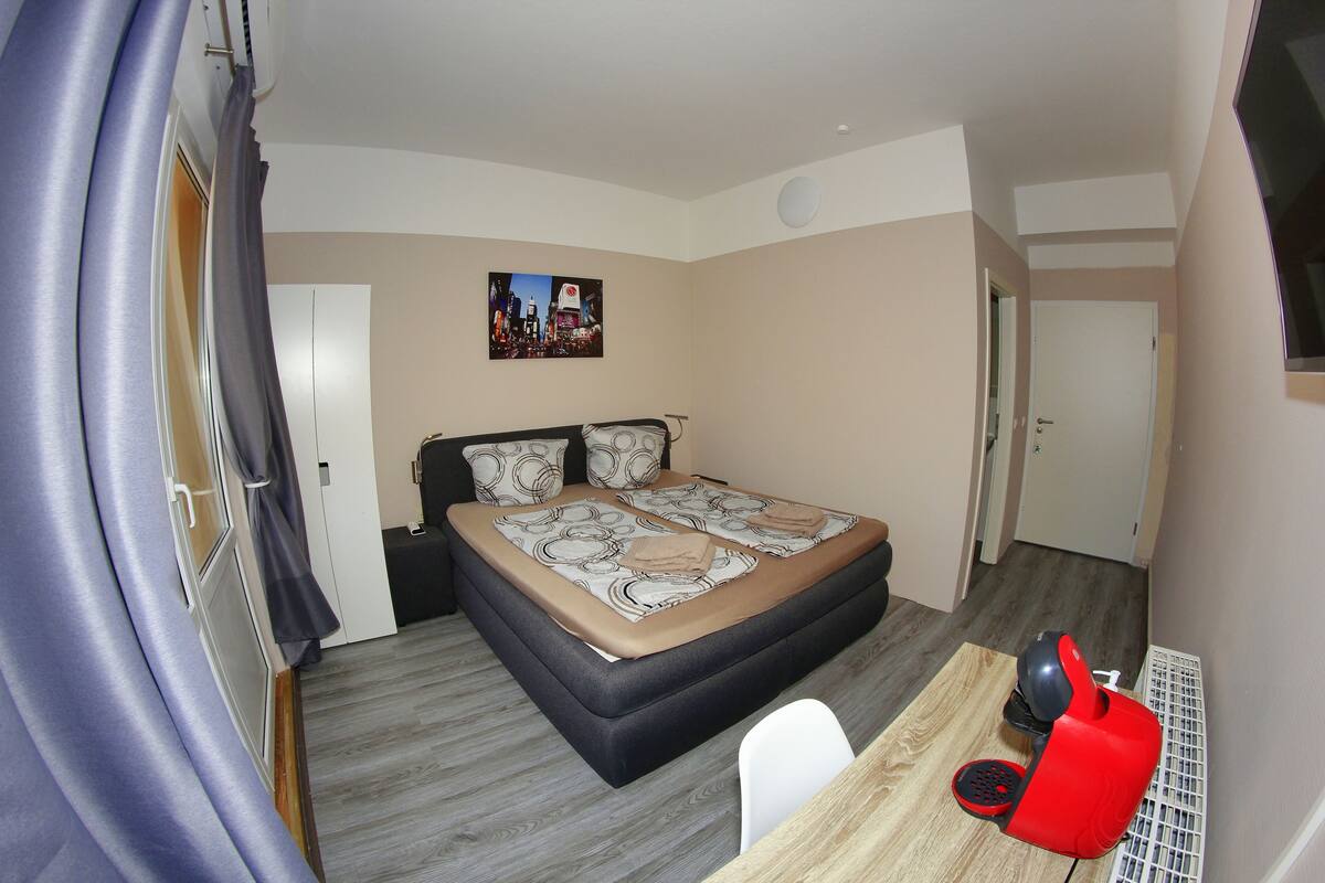 A bedroom with a bed, a desk, and a chair.