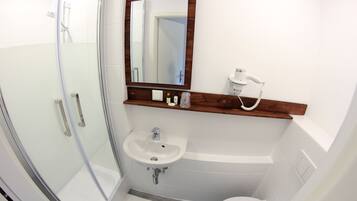 A bathroom with a glass shower enclosure, a sink, a toilet, and a mirror with a wooden frame.