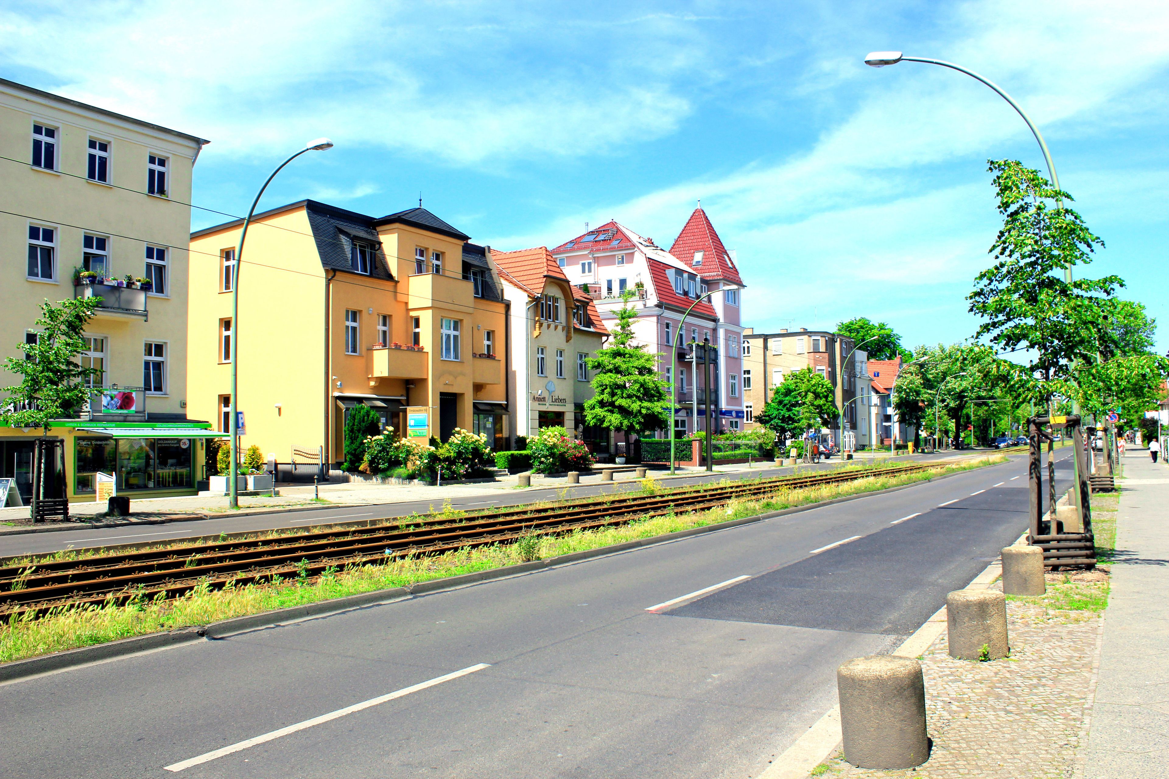 A street with buildings, a sidewalk, and a train track.