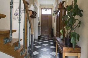 Ein Flur mit Schachbrettmuster, einer Holztreppe und einem Blumentopf.