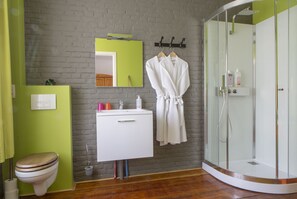 Ein Badezimmer mit einer hölzernen Toilette, einem weißen Waschbecken mit Spiegel darüber und einer Duschkabine aus Glas.