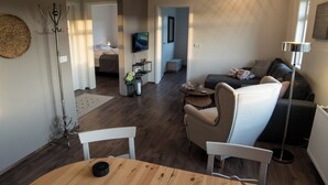 A modern living room with a sofa, armchairs, a dining table, and a TV. - Breidamyri Farm Apartments (Laugar)