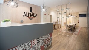 A reception area with a wooden wall, a counter, and a dining area with a table and chairs. - Almada Wine House (Porto)