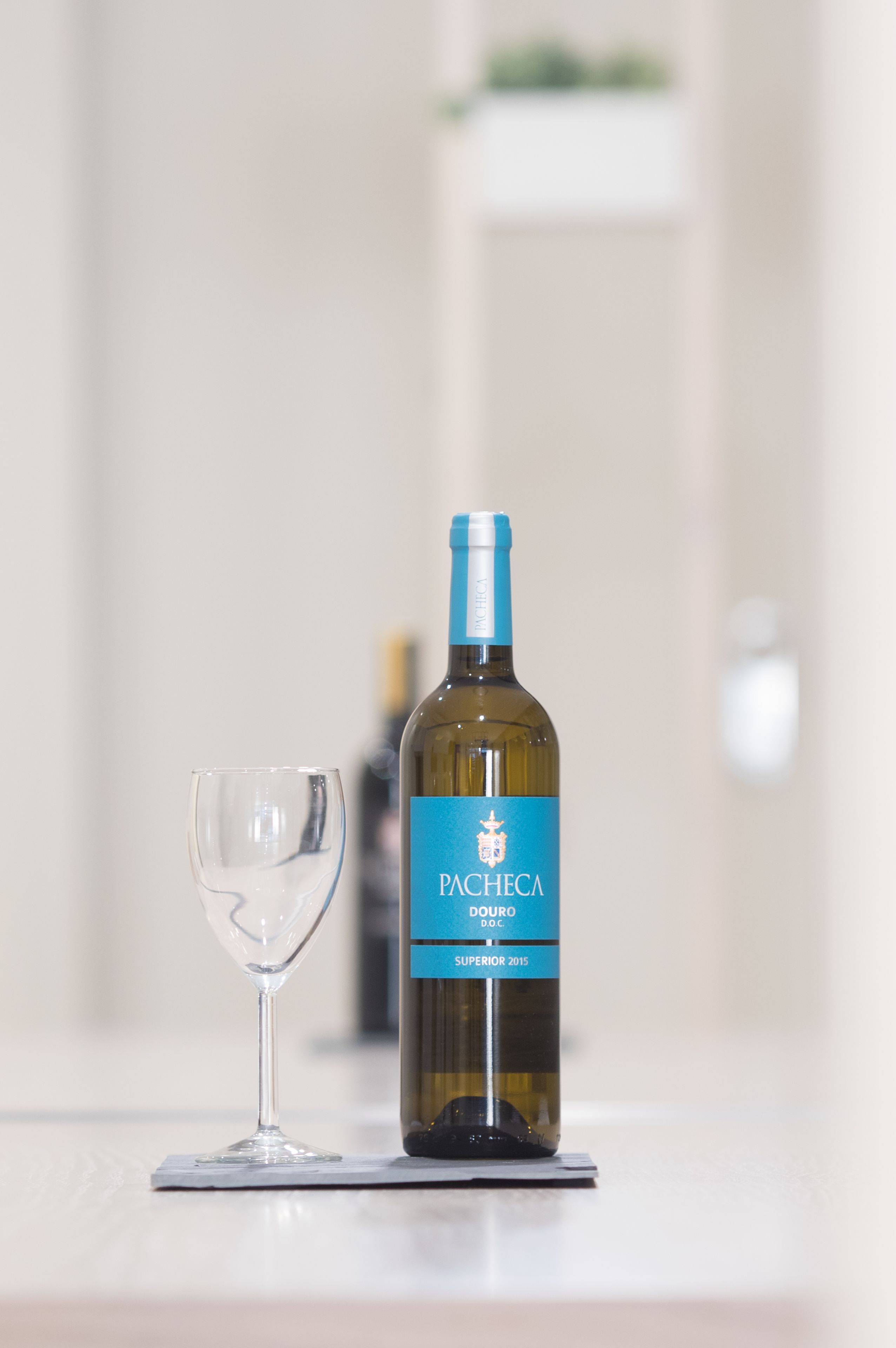 A bottle of Pacheta Douro DOC Superior 2015 wine and a wine glass on a table.