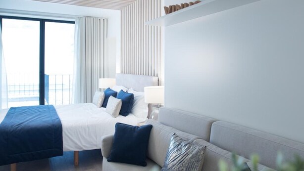 A modern hotel room with a bed, a sofa, and a large window. - Almada Wine House (Porto)