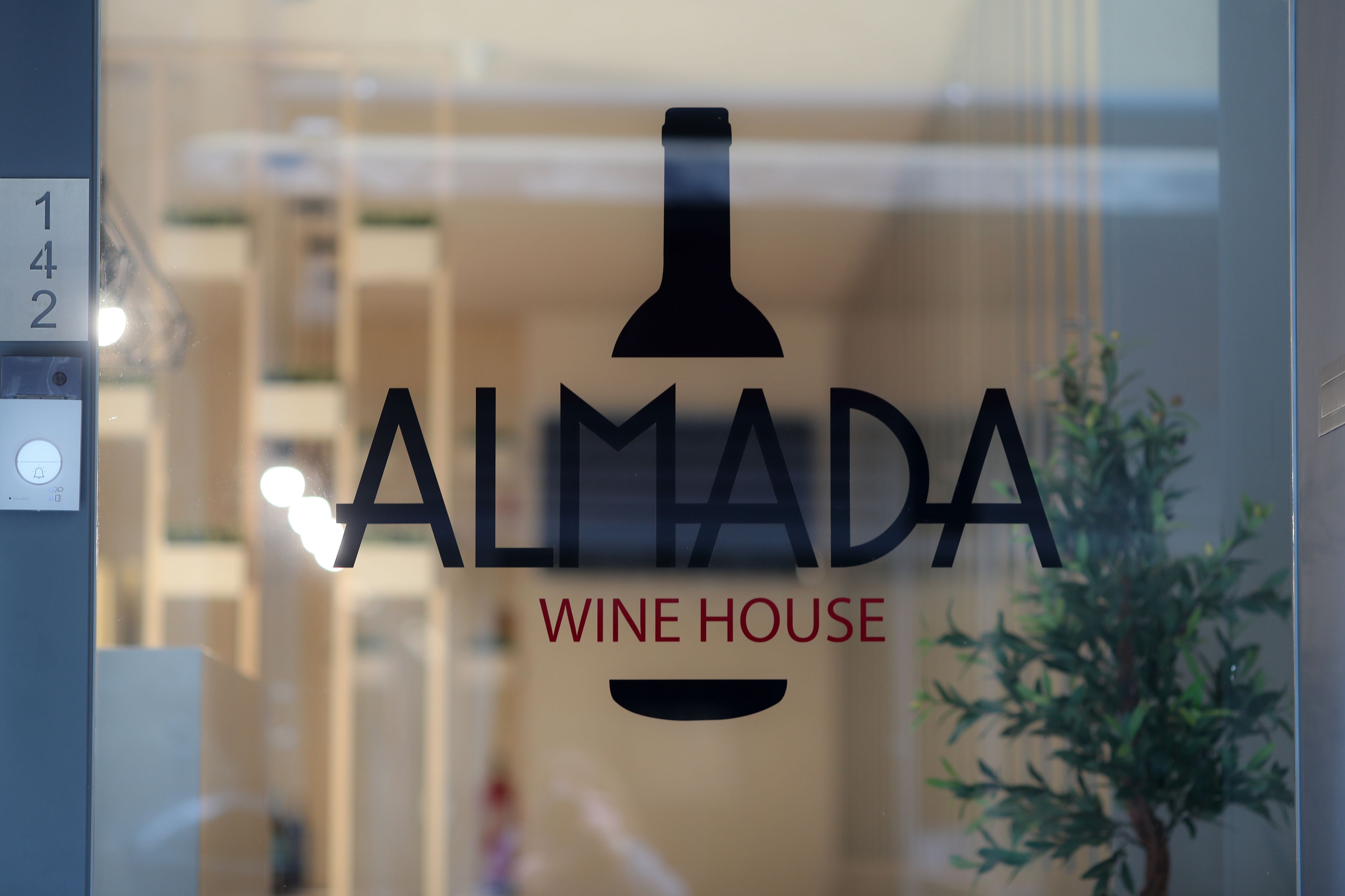 En glasdörr med logotypen ”ALMADA WINE HOUSE” och numret ”142” på vänster sida.