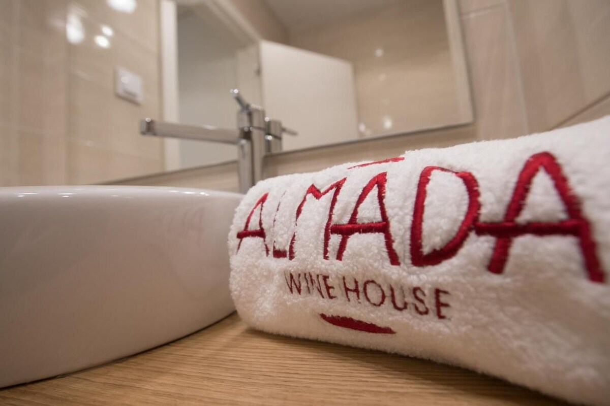 A white towel with embroidered text "ALMADA WINE HOUSE" on a bathroom counter.