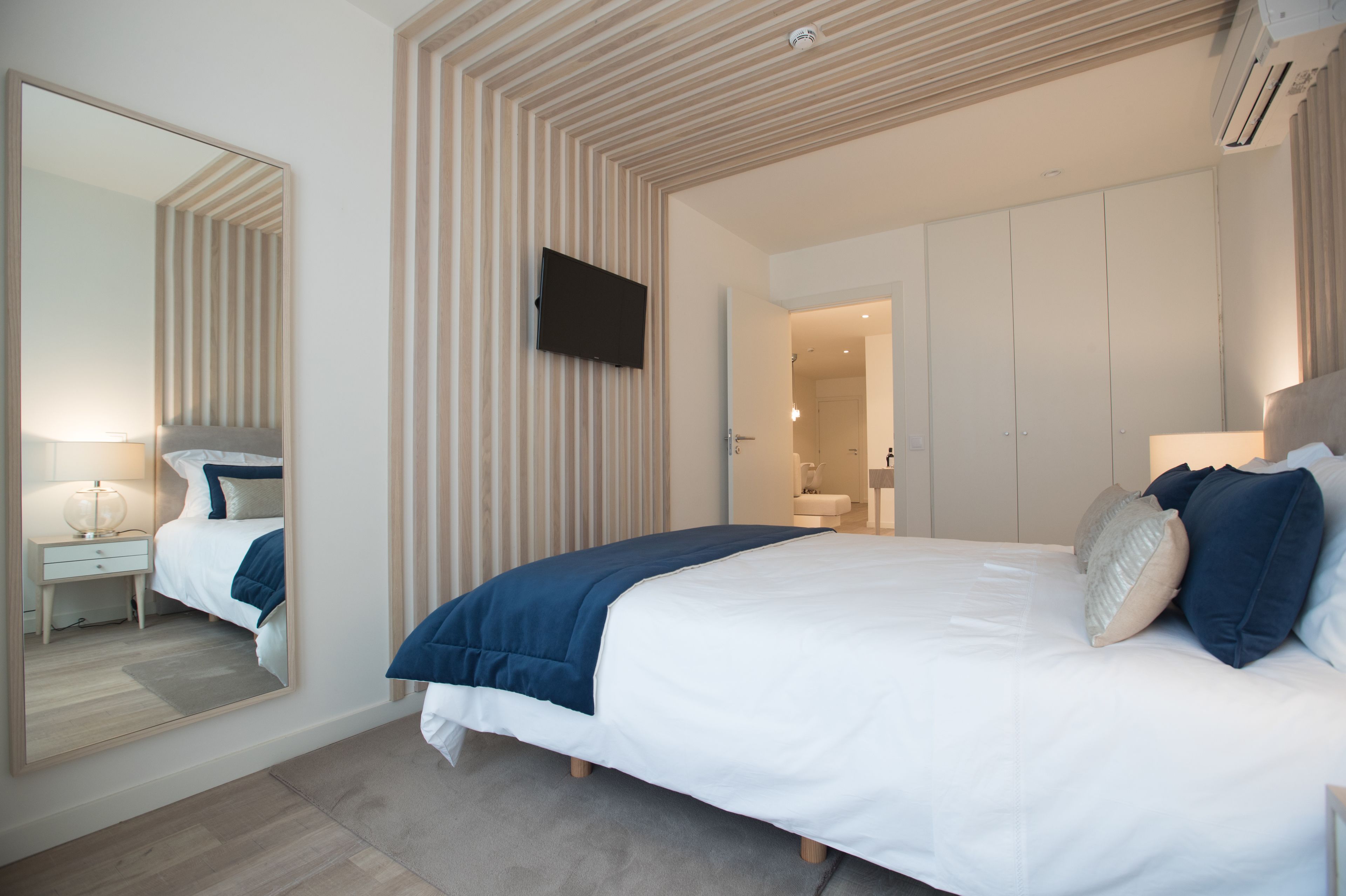Un dormitorio moderno con una cama grande, un televisor de pantalla plana en la pared y un vestidor.