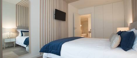 Un dormitorio moderno con una cama grande, un televisor de pantalla plana en la pared y un vestidor.