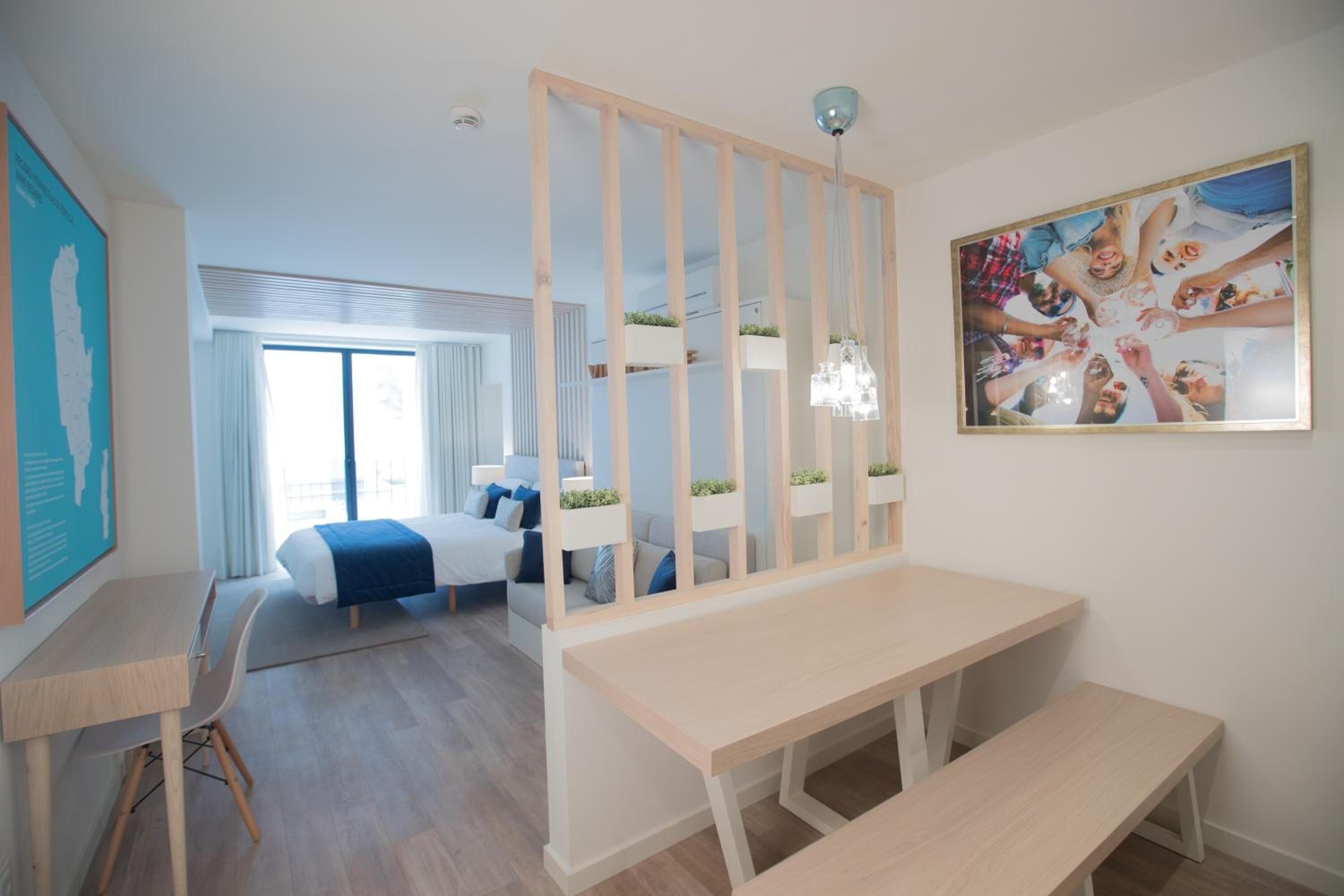 Une chambre d’hôtel moderne dotée d’un grand lit, d’un bureau, d’une banquette, d’un paravent décoratif et d’une grande fenêtre.